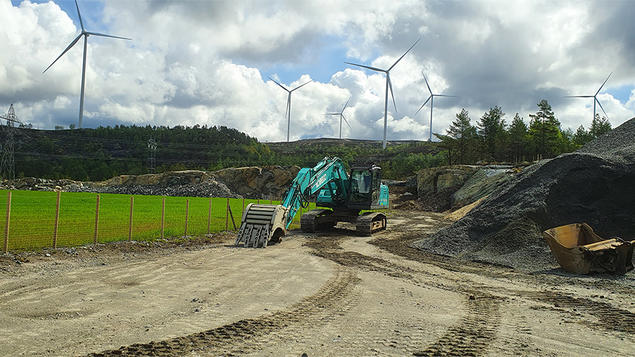 Anleggsområde med en gravemaskin og i bakgrunnen vindturbiner i snaufjlellsområde Tonstad vindpark i Sirdal (mai 2022). Foto: Lars H. Gulbrandsen